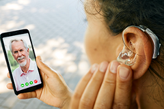photo of a woman wearing a hearing aid in a video chat on a smartphone
