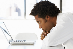 photo of a man looking at a laptop screen