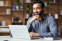 photo of a man reading on a laptop