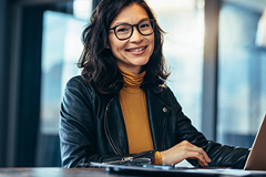 photo of a woman at a laptop computer, smiling