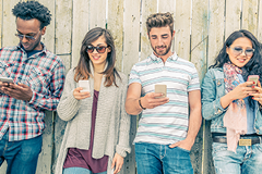 photo of 4 young adults looking at their smartphones