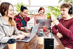 photo of gen z people sitting at a table with laptops