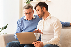 photo of a younger man explaining something on a laptop to an older man