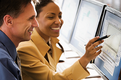 photo of 2 people studying data on a computer screen