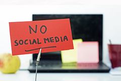 photo of a sign reading "no social media" imposed over a laptop computer in the background