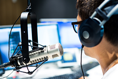 photo of a woman speaking into a microphone wearing headphones