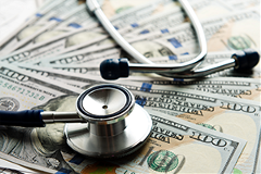photo of  stethoscope lying on top of currency