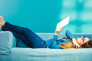 emails photo of a young woman reclining on a sofa looking at a tablet