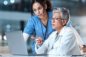 physician-co-lead photo of 2 medical people looking at a laptop